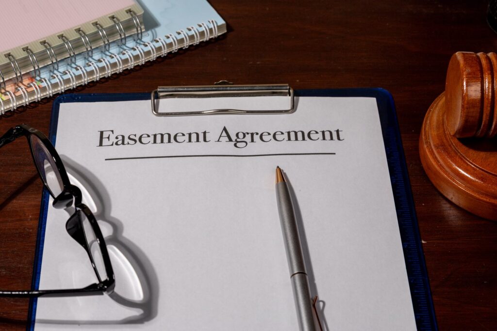 A clipboard with paperwork that says Easement Agreement next to a gavel and glasses